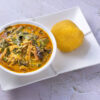 Nigerian food, Oha soup with beef served with garri on a white plate.