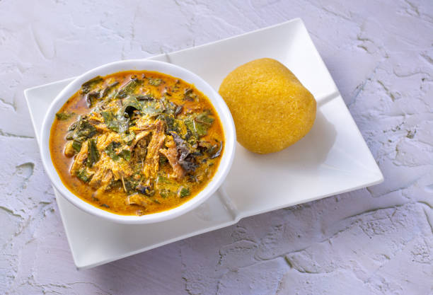 Nigerian food, Oha soup with beef served with garri on a white plate.